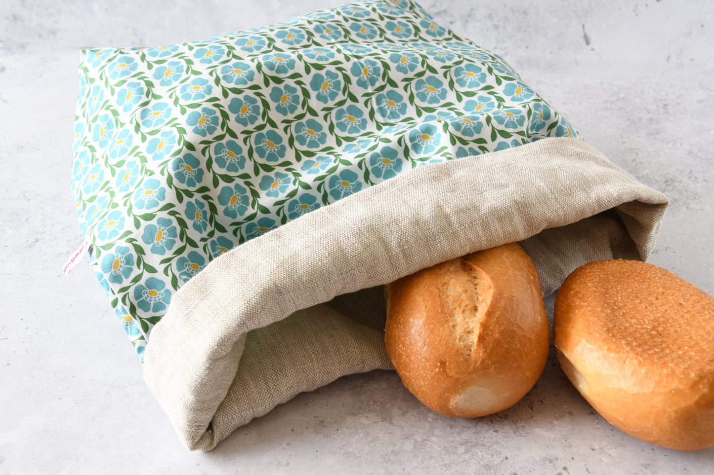 Nahaufnahme des flach liegenden Brotbeutels „Franziska“ aus hochwertigem Leinenstoff mit verspieltem Blumenmuster.