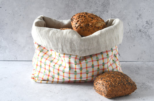 Nachhaltiger Brotbeutel Karoline orange mit umgekrempeltem Rand, servierbereit als farbenfroher Brotkorb aus Stoff.