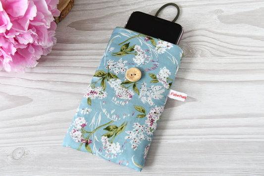 Geöffnete Stoff-Handyhülle mit Blumenmuster und einem Smartphone, das darin sicher vor Kratzern geschützt wird.