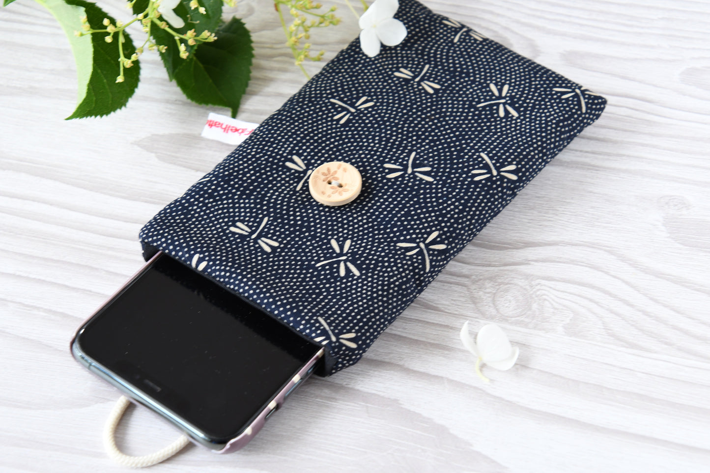 Geöffnete Stoff-Handyhülle mit einem Smartphone, das darin sicher vor Kratzern geschützt wird.