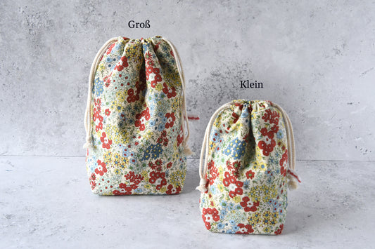 Größenvergleich der handgemachten Kinchaku-Beutel mit rotfarbenem Streublumen-Muster von Fabelhafte Werkstatt: Das kleine und große Modell nebeneinander.