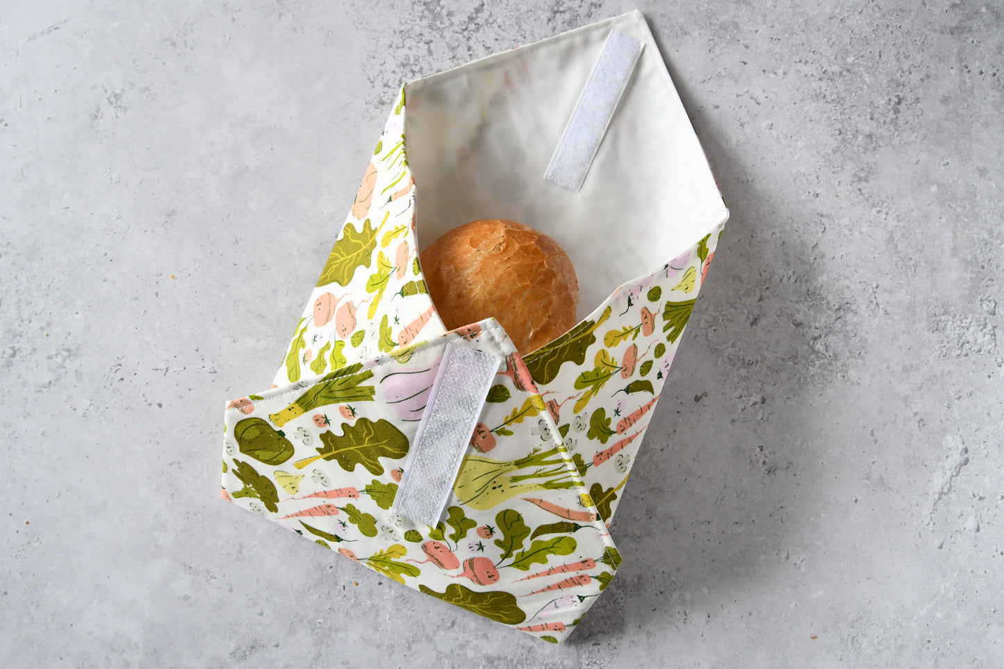 Schritt-für-Schritt-Anleitung: Der waschbare Sandwich Wrap ist an drei Seiten um das Brötchen gefaltet, kurz vor dem Verschließen.