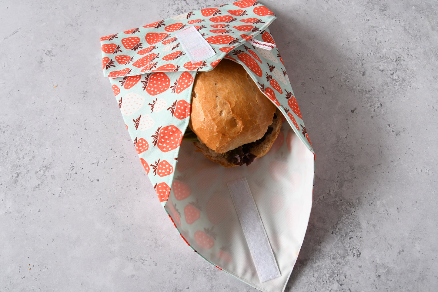 Sicheres Verpacken für unterwegs: Drei Seiten des wasserfesten Sandwich Wraps sind über dem Pausenbrot eingeklappt.