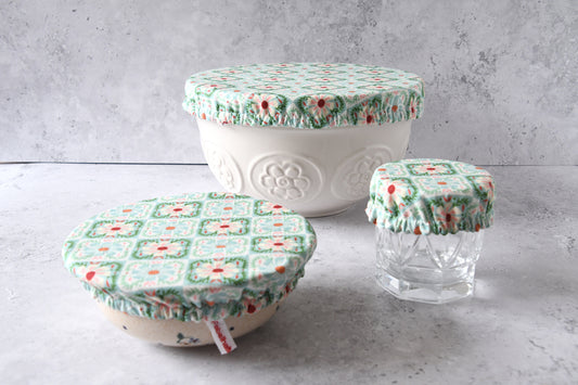Drei handgenähte Schüsselhauben im karolierten Mint-Blumenmuster in den Größen S, M und L im Vergleich.