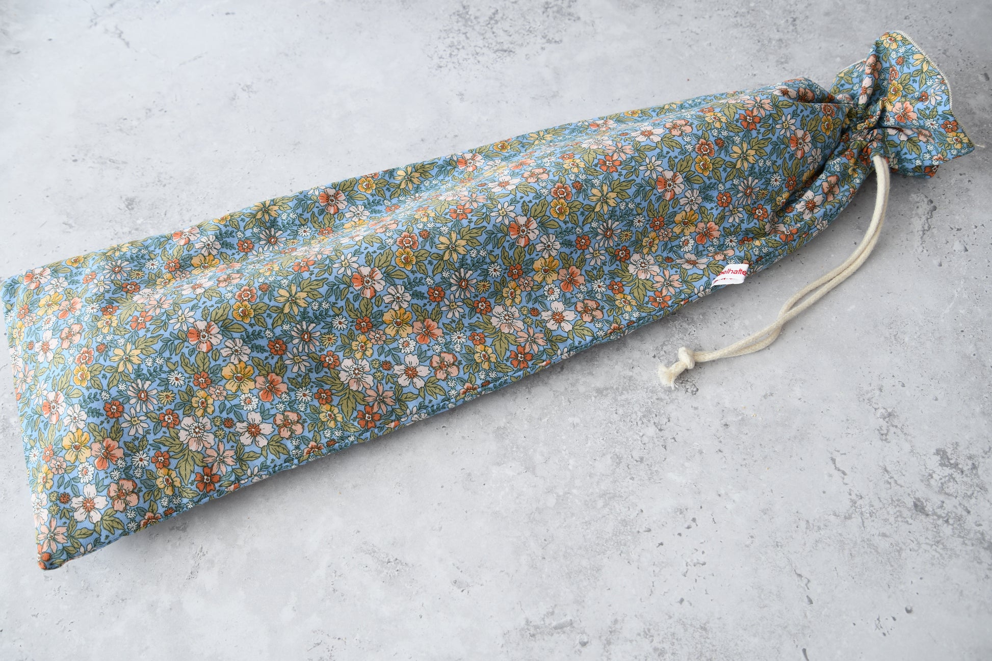 Ein handgefertigter, schmaler Baguettebeutel  liegt flach ausgebreitet auf hellem Untergrund. Der Beutel ist am oberen Ende mit einer robusten Kordel fest zugezogen.
