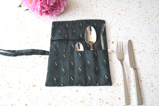 Handgenähte Besteckrolle aus Stoff mit Blumenmuster, geöffnet und mit Messer, Gabel und Löffel in den Fächern bestückt.