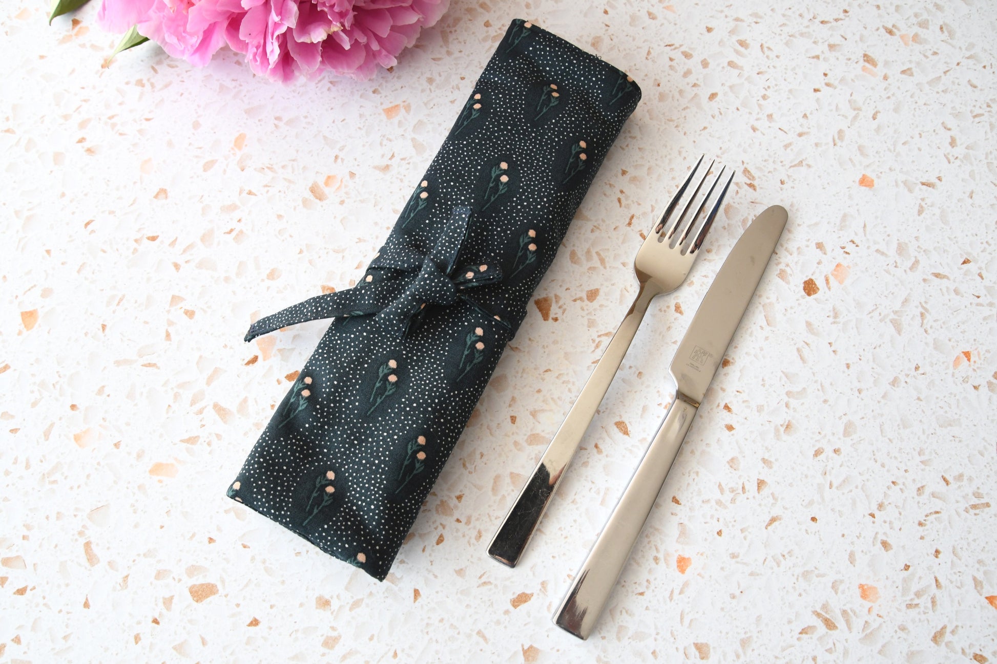 Zusammengerollte und mit einem Band zubundene Bestecktasche mit floralem Blumenmuster von Fabelhaftewerkstatt.