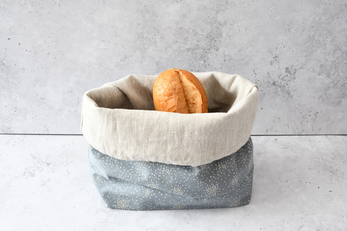 Brotbeutel von Fabelhaftewerkstatt aus Baumwolle "Glitter auf grau", der umgeklappt als Brotkorb mit frischen Brötchen steht.