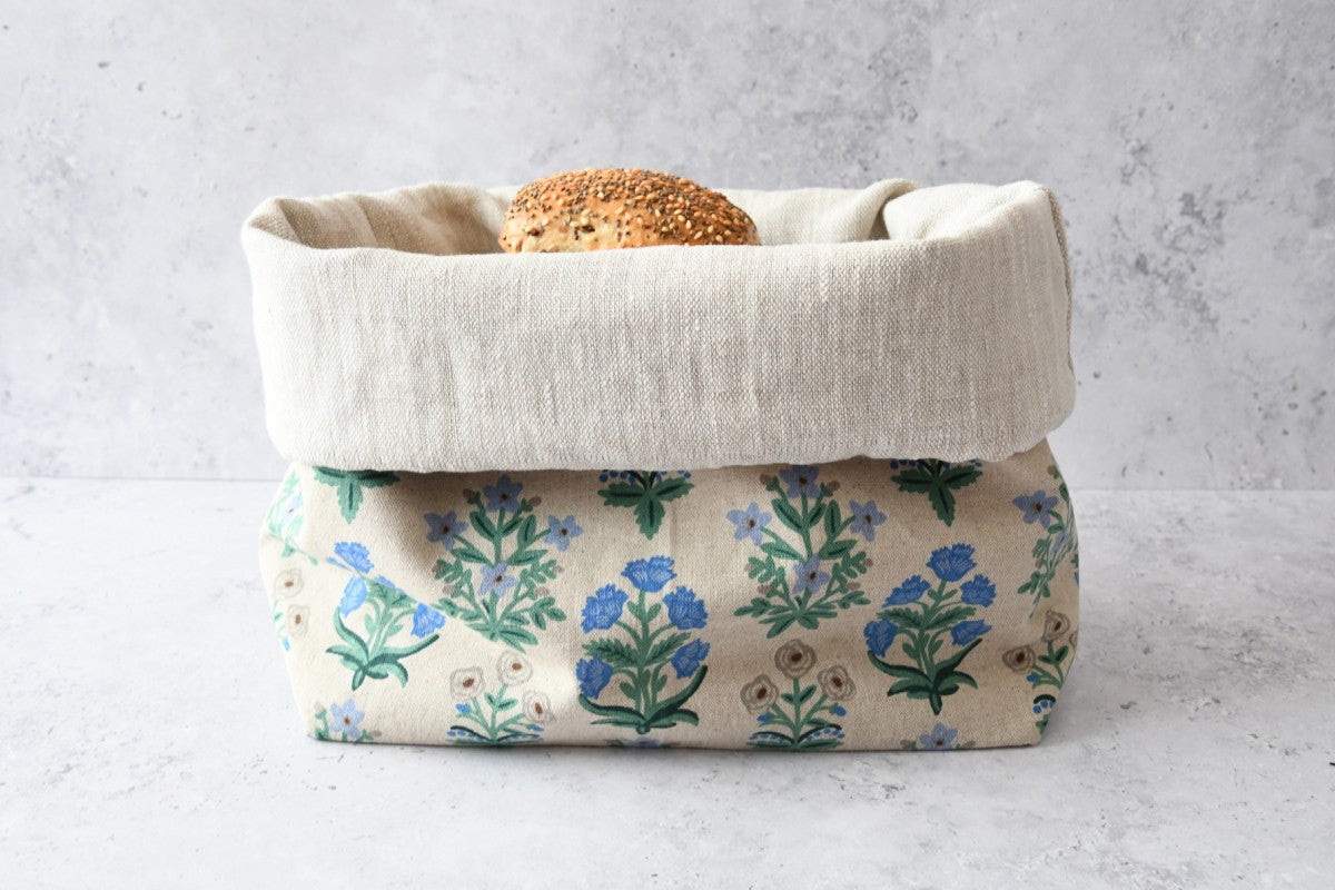 Brotbeutel "Elodie blau" von Fabelhaftewerkstatt aus Baumwolle mit Leinen, der umgeklappt als Brotkorb mit frischen Brötchen steht.