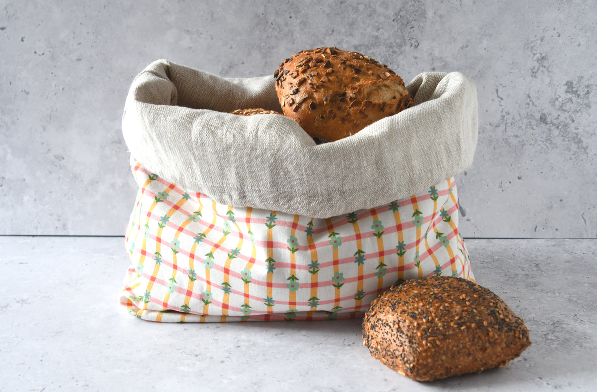 Nachhaltiger Brotbeutel Karoline orange mit umgekrempeltem Rand, servierbereit als farbenfroher Brotkorb aus Stoff.