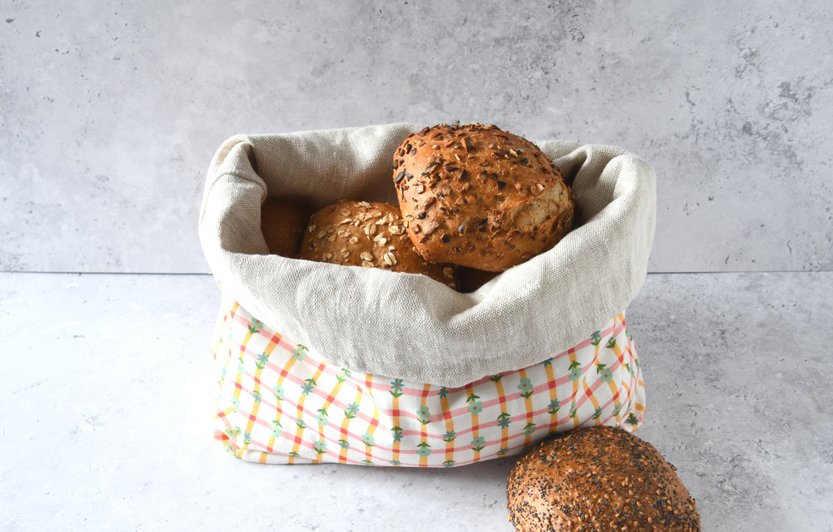 Nachhaltiger Brotbeutel Karoline orange mit umgekrempeltem Rand, servierbereit als farbenfroher Brotkorb aus Stoff.