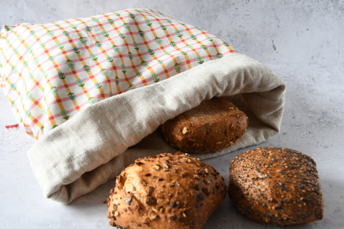 Brotbeutel Karoline orange flach liegend mit aufgeschlagenem Saum, zeigt das naturbelassene Innenfutter aus reinem Leinen.
