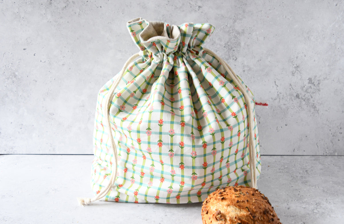 Wiederverwendbarer Brotbeutel Karoline grün aus Baumwolle mit kariertem Blumenmuster, geschlossen für die frische Aufbewahrung von Brot und Brötchen.