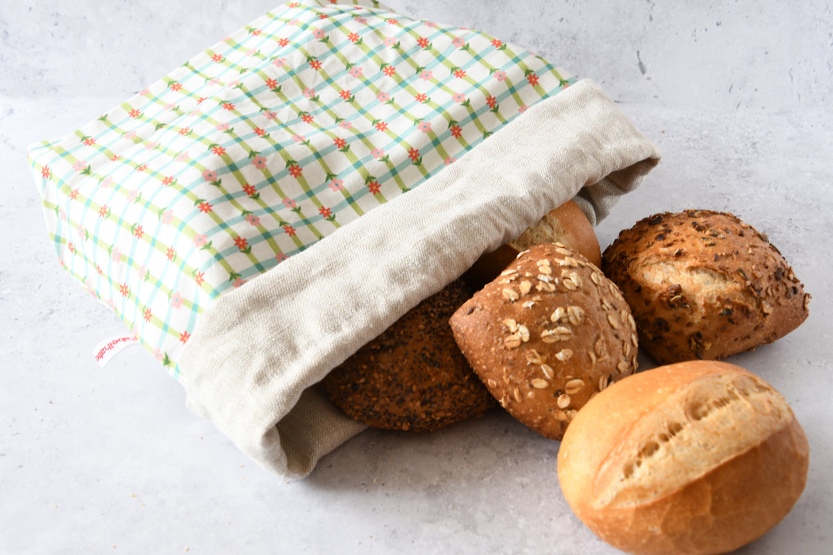 Brotbeutel Karoline grün flach liegend mit aufgeschlagenem Rand, zeigt das atmungsaktive Innenfutter aus reinem Leinen.