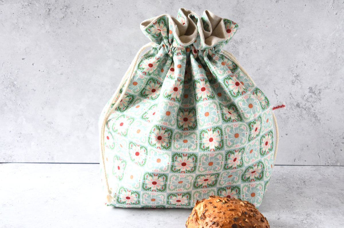 Wiederverwendbarer Brotbeutel Elisa aus Baumwolle mit Karo- und Blumenmuster in Mint, geschlossen zur frischen Aufbewahrung von Brot und Brötchen.