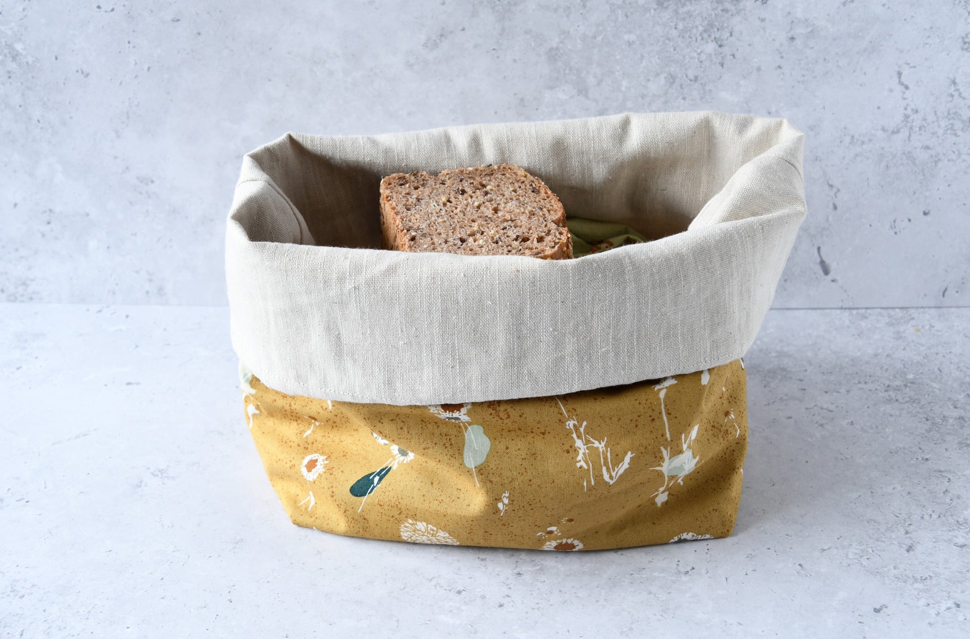 Brotbeutel "Amber" von Fabelhaftewerkstatt aus Baumwolle und Leinen, der umgeklappt als Brotkorb mit frischen Brötchen steht.