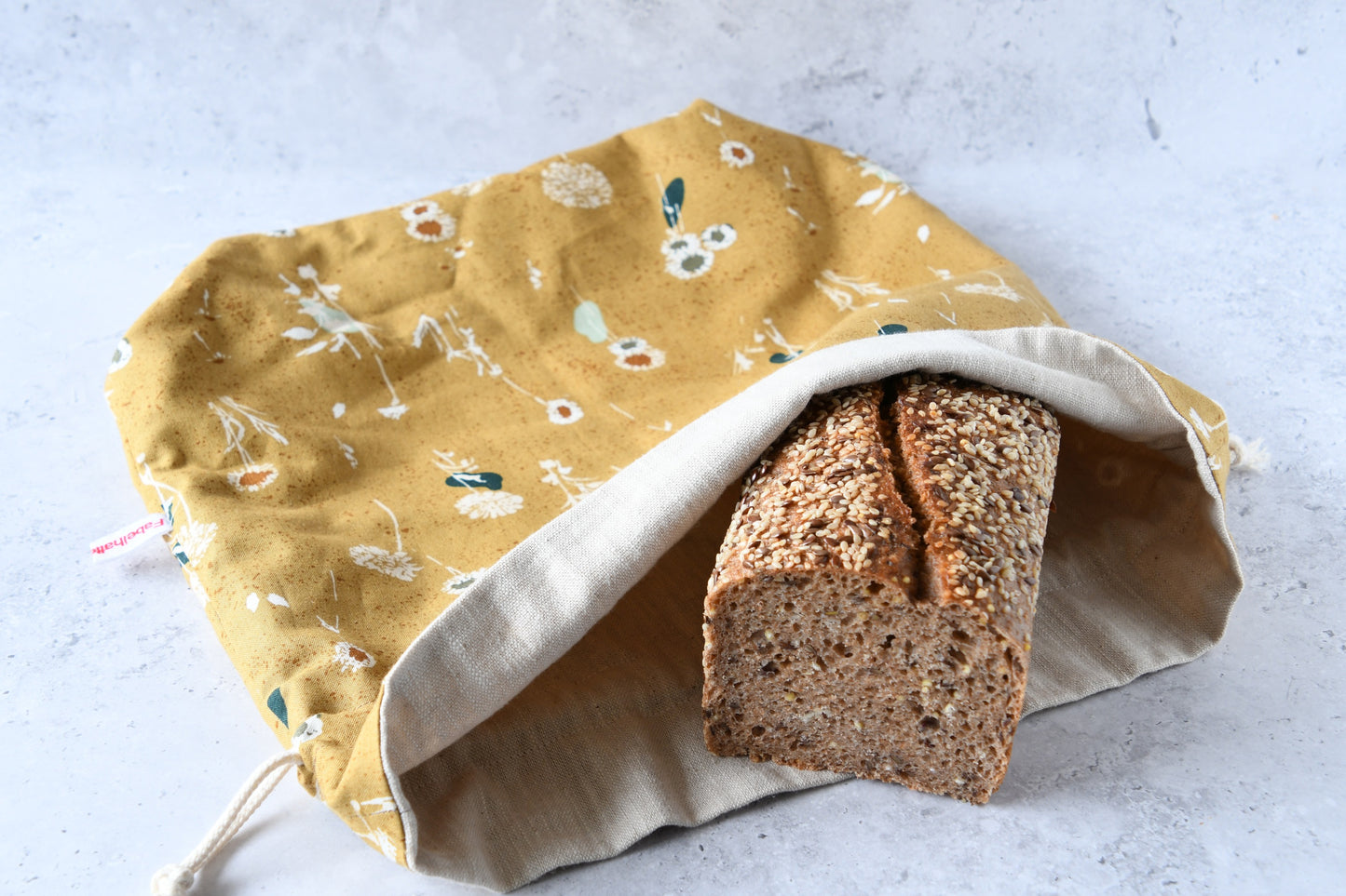 Liegender Brotbeutel "Amber" aus Baumwolle, bei dem das atmungsaktive Innenfutter aus 100% Leinen gut zu sehen ist, von Fabelhaftewerkstatt.