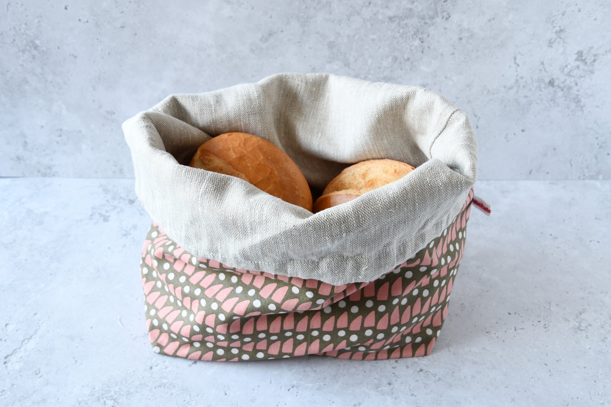 Brotbeutel "Eva" von Fabelhaftewerkstatt aus Baumwolle und Leinen, der umgeklappt als Brotkorb mit frischen Brötchen steht.