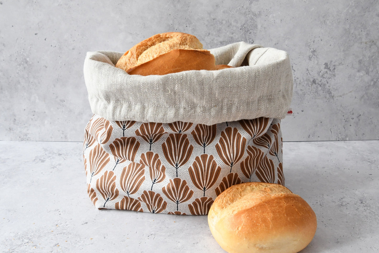 Brotbeutel "Tulipa" von Fabelhaftewerkstatt aus Baumwolle und Leinen, der umgeklappt als Brotkorb mit frischen Brötchen steht.