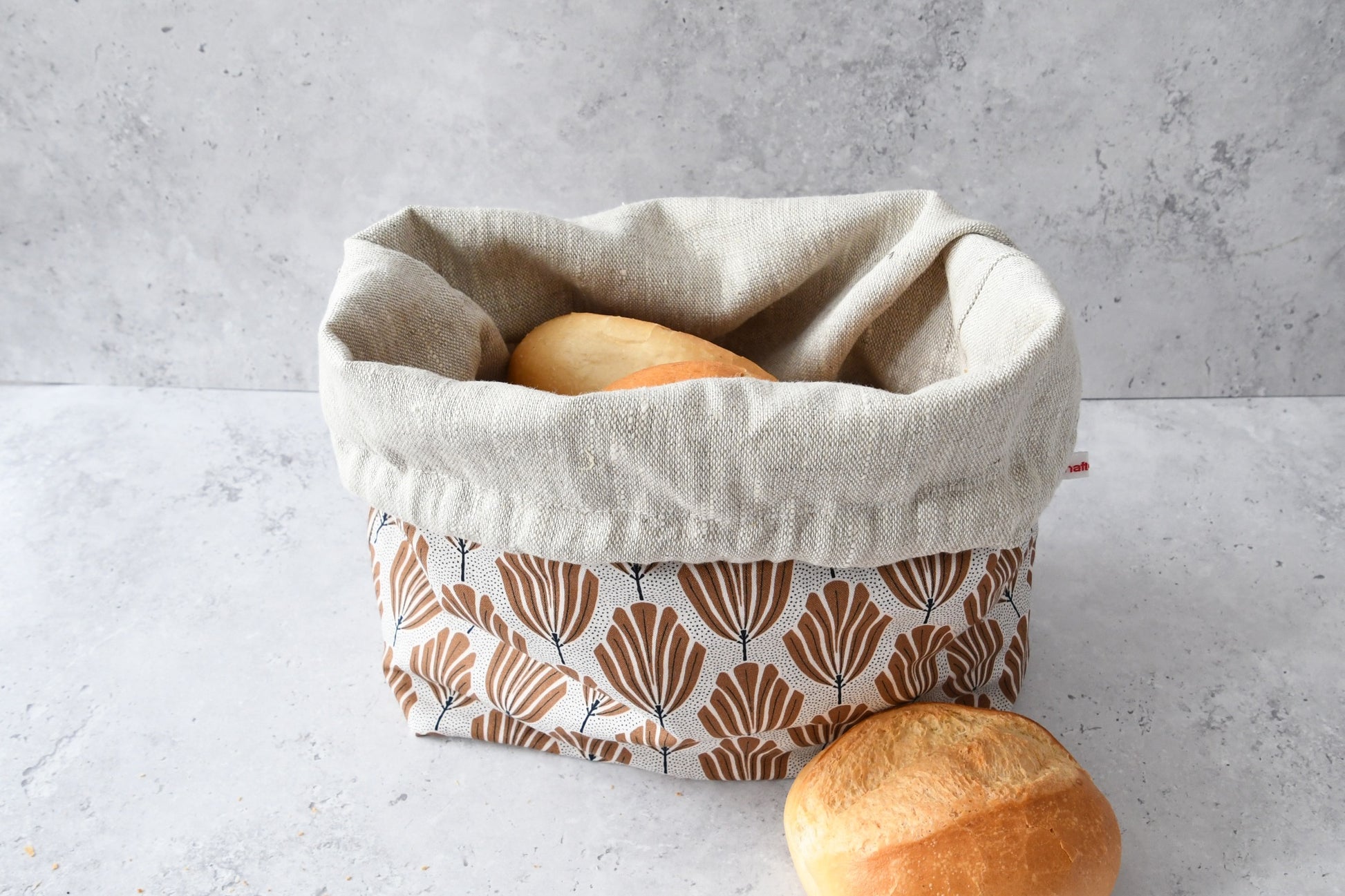 Brotbeutel "Tulipa" von Fabelhaftewerkstatt aus Baumwolle und Leinen, der umgeklappt als Brotkorb mit frischen Brötchen steht.