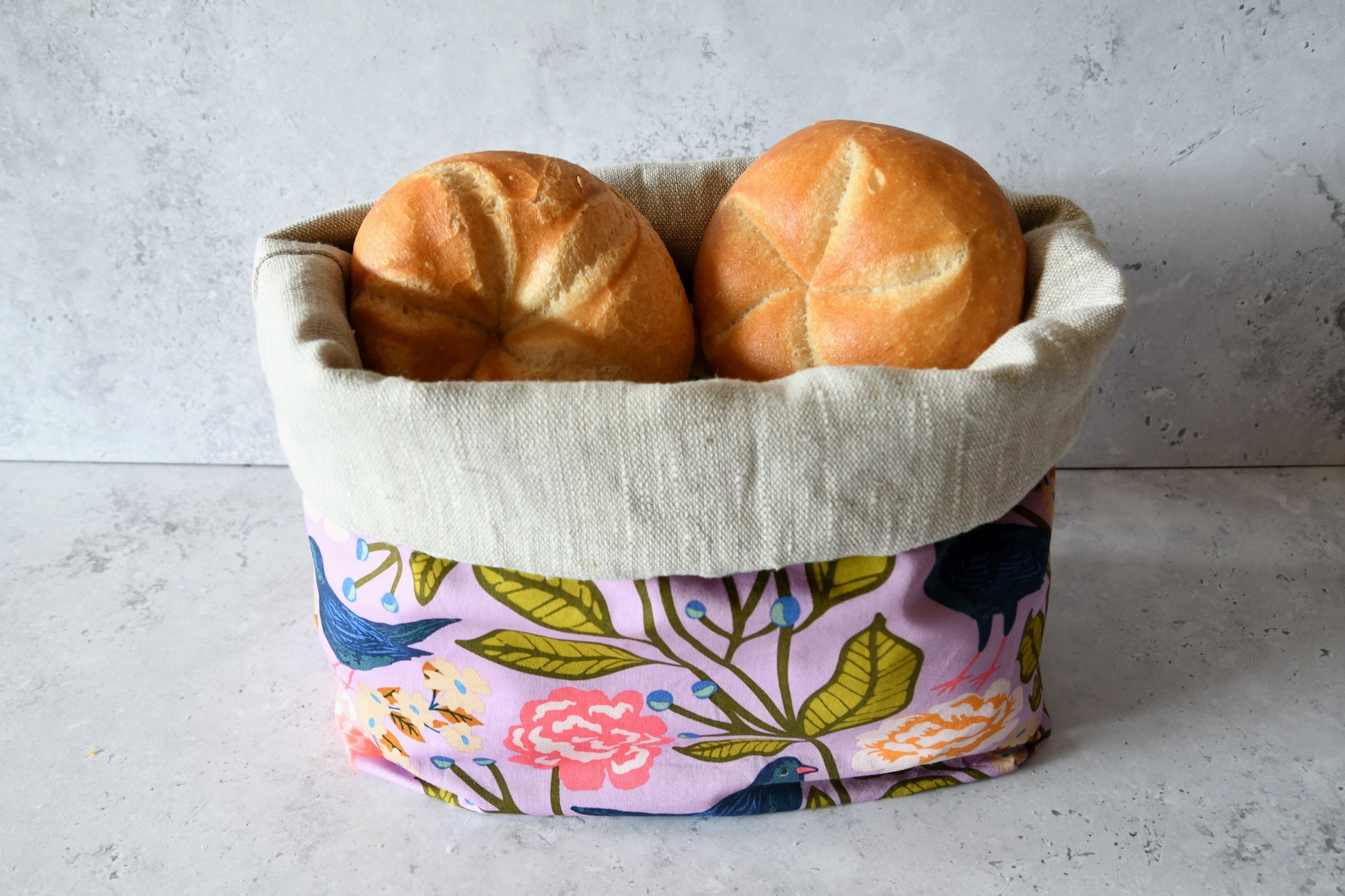 Brotbeutel "Agnes" von Fabelhaftewerkstatt aus Baumwolle und Leinen, der umgeklappt als Brotkorb mit frischen Brötchen steht.