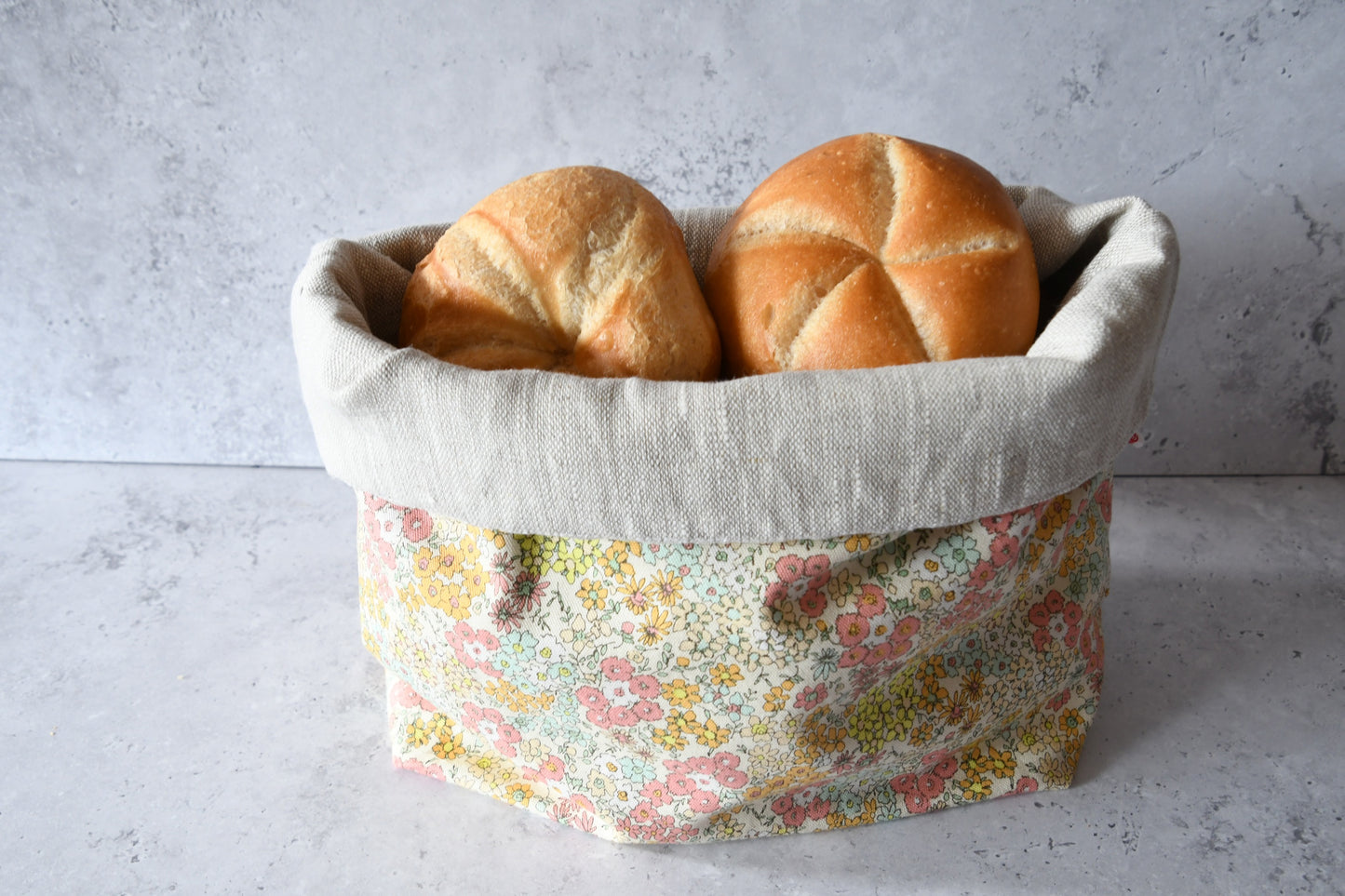 Brotbeutel "Hikari" von Fabelhaftewerkstatt aus Baumwolle und Leinen, der umgeklappt als Brotkorb mit frischen Brötchen steht.