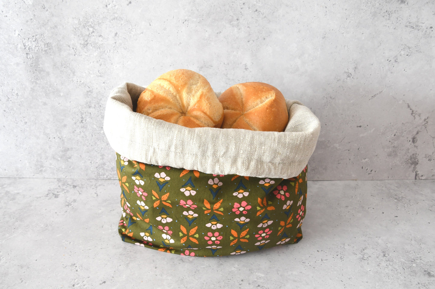 Brotbeutel "Colette" von Fabelhaftewerkstatt aus Baumwolle und Leinen, der umgeklappt als Brotkorb mit frischen Brötchen steht.