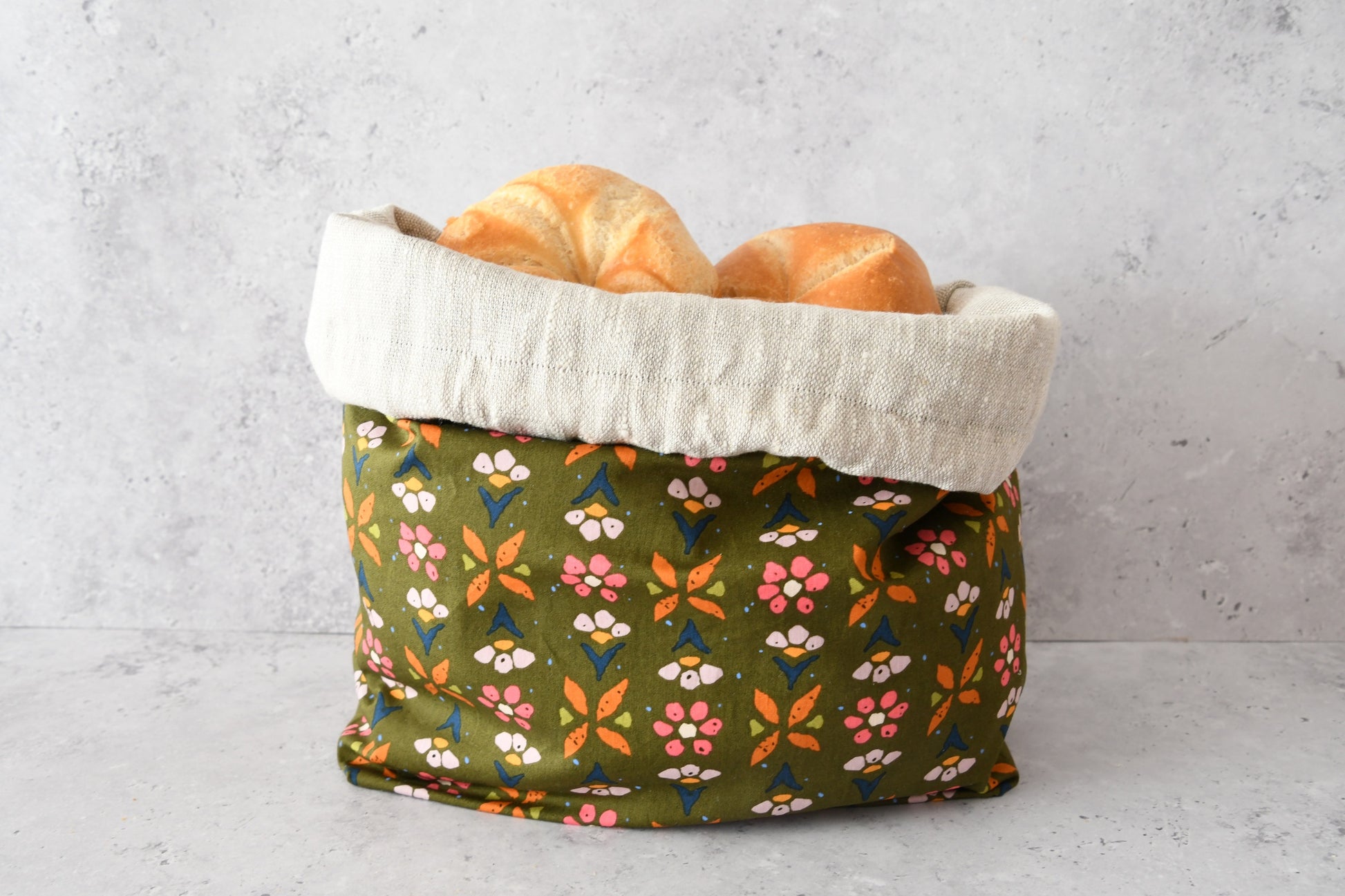 Brotbeutel "Colette" von Fabelhaftewerkstatt aus Baumwolle und Leinen, der umgeklappt als Brotkorb mit frischen Brötchen steht.