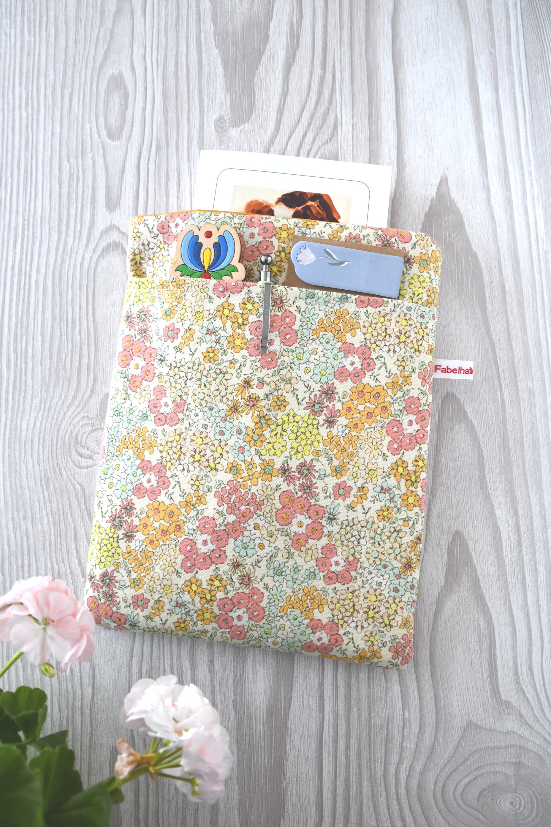 Gepolsterte Buchtasche aus Baumwolle mit rosa Streublumen-Muster, flach von oben fotografiert.