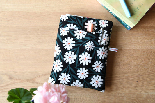 Fröhliche, weich gepolsterte Buchtasche mit einem sommerlichen Margeriten-Muster (weiße Blüten mit orangenfarbender Mitte).  Im cleveren Vorderfach sind Stifte und kleine Haftnotizen griffbereit platziert.