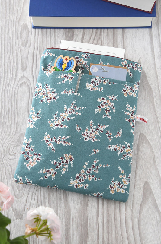 Handgefertigte, gepolsterte Buchtasche der Fabelhaften Werkstatt mit einem eleganten Muster aus Wisteria-Zweigen (Blauregen). Auf der flach liegenden Hülle ist das praktische, aufgesetzte Vorderfach gut zu erkennen.