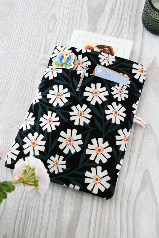 Fröhliche, weich gepolsterte Buchtasche mit einem sommerlichen Margeriten-Muster (weiße Blüten mit orangenfarbender Mitte).  Im cleveren Vorderfach sind Stifte und kleine Haftnotizen griffbereit platziert.