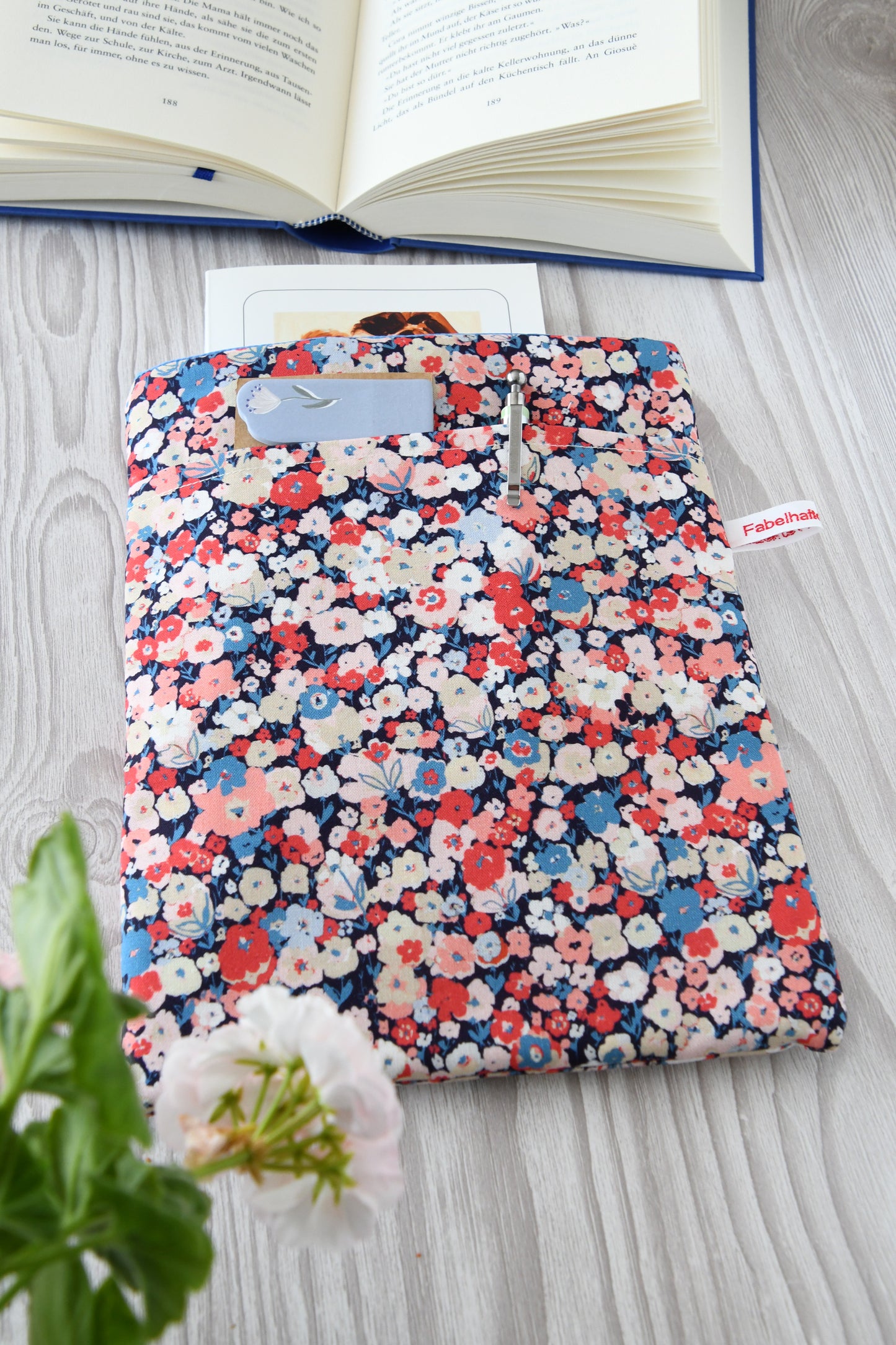 Gepolsterte Buchtasche Jenifer aus Baumwolle mit buntem Blumenkonfetti-Muster, flach von oben fotografiert.