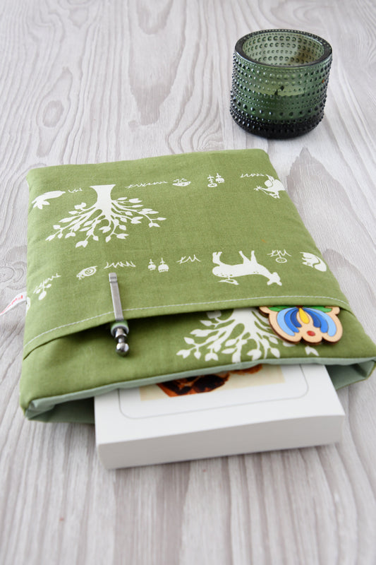 Gemütliche Buchhülle mit Waldtier-Motiv. Ein Taschenbuch ist in der weich gepolsterten Tasche verstaut, während im praktischen Extra-Fach auf der Vorderseite Stift und Lesezeichen stecken.