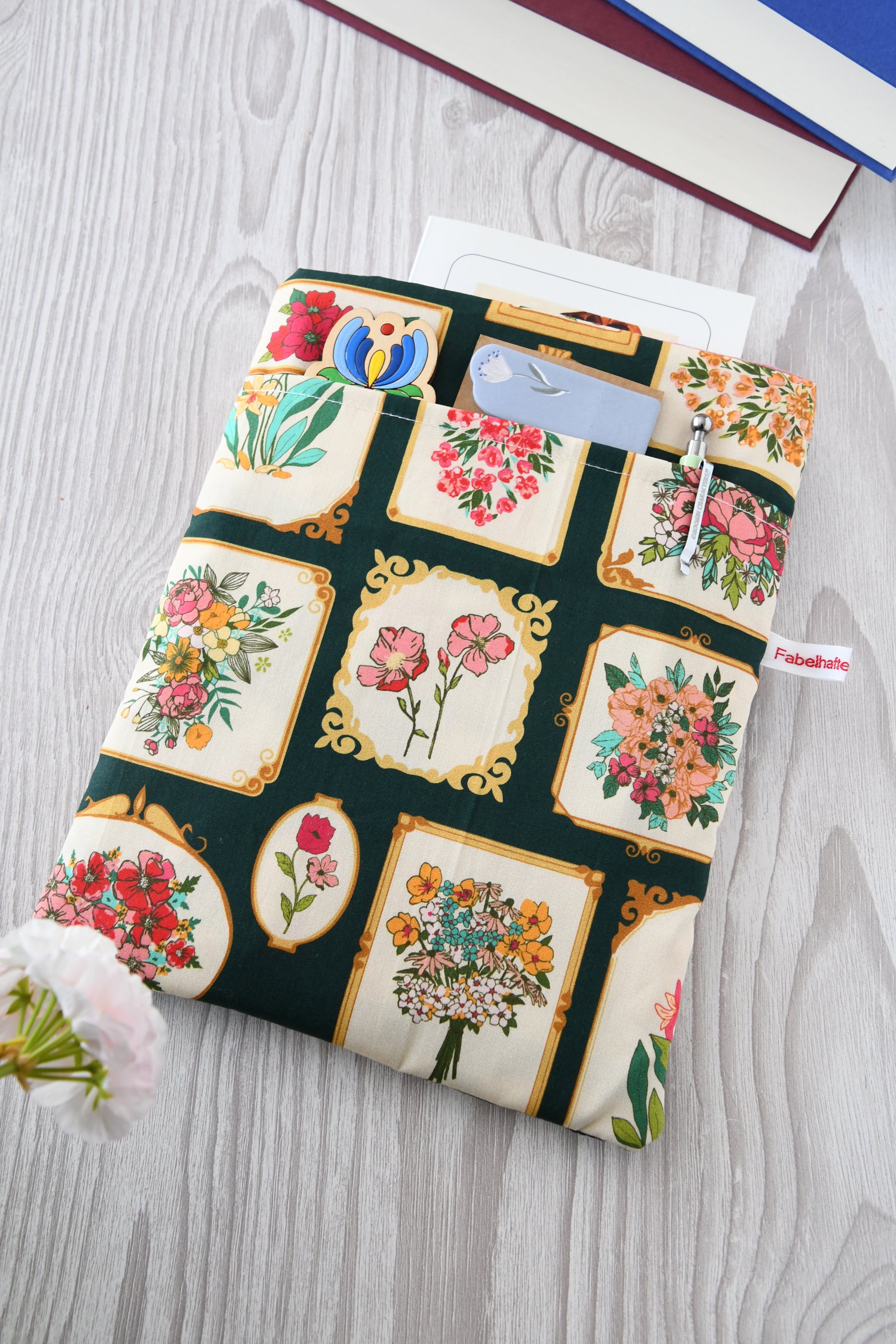 Gepolsterte Buchtasche Bildergalerie aus Baumwolle mit eingerahmten Blumenbildern, flach von oben fotografiert.