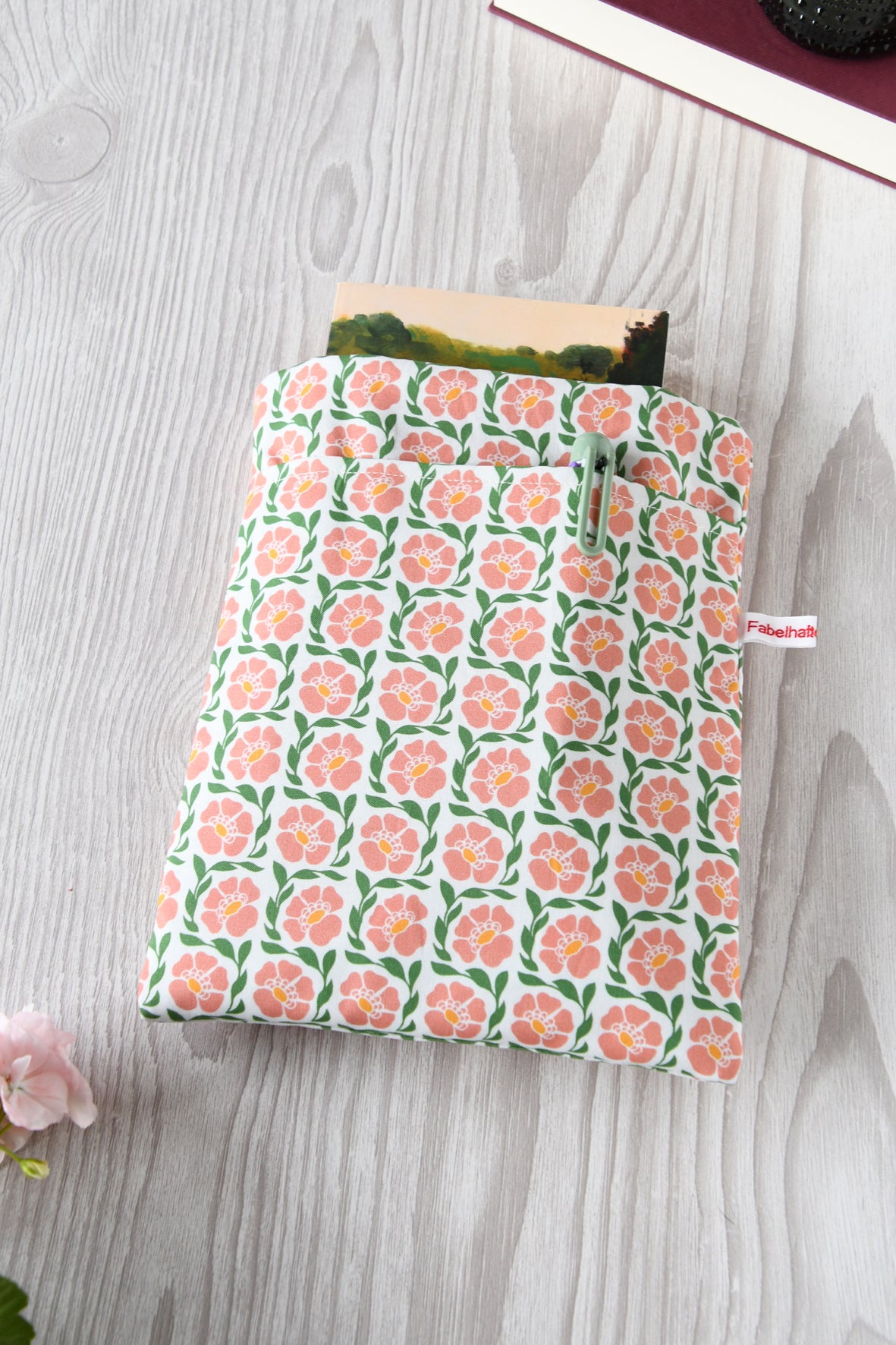 Handgenähte Buchtasche "Fanny" aus Baumwollstoff mit rosafarbendem Blumenmuster. Sichtbar ist das Hauptfach sowie die praktische Vordertasche über die gesamte Breite für Stifte und Lesezeichen.
