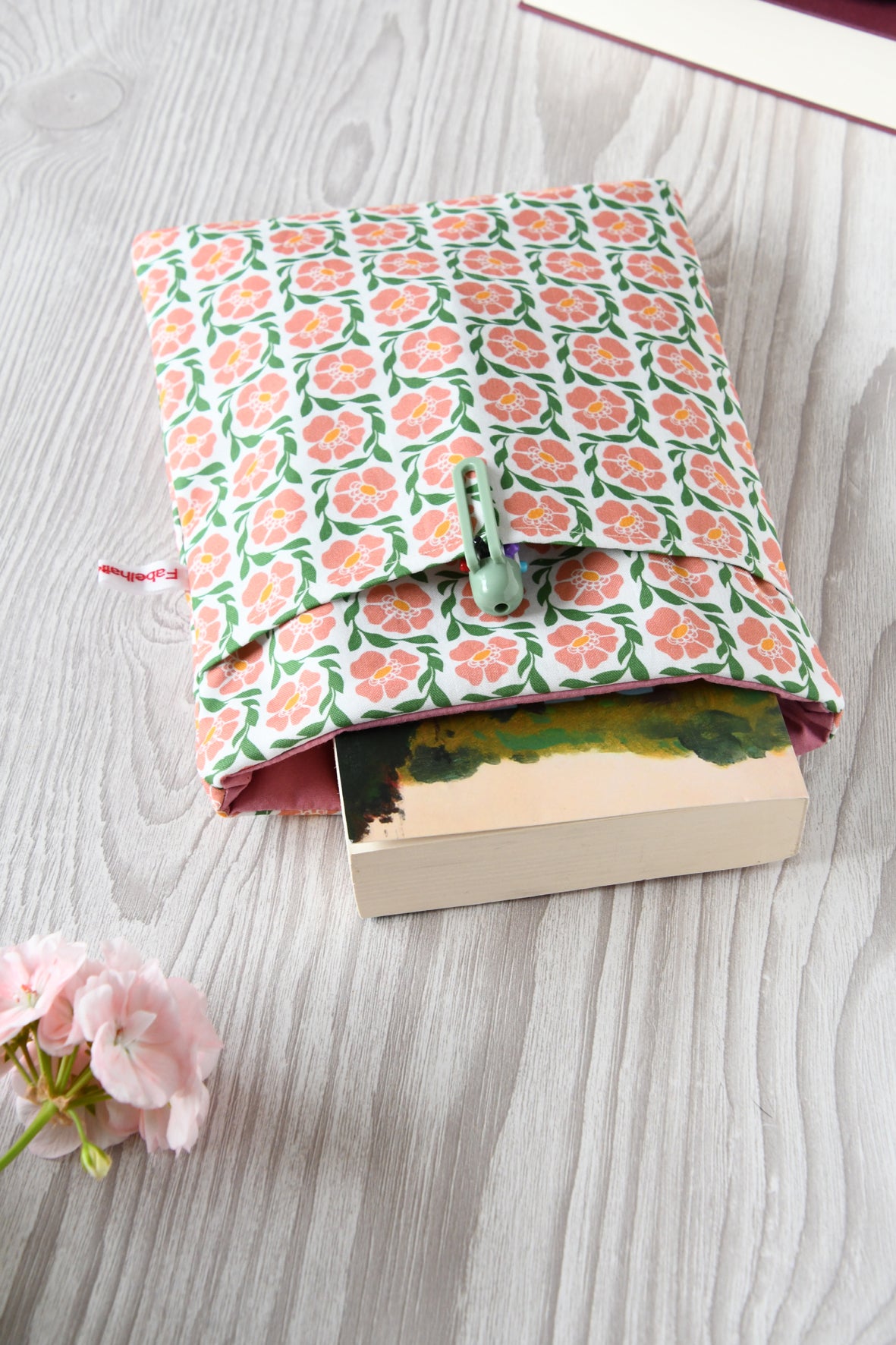 Buchtasche "Fanny" in Standardgröße M mit rosafarbendem Blumenmuster. Ein gängiges Taschenbuch steckt perfekt geschützt in der gepolsterten Buchhülle.