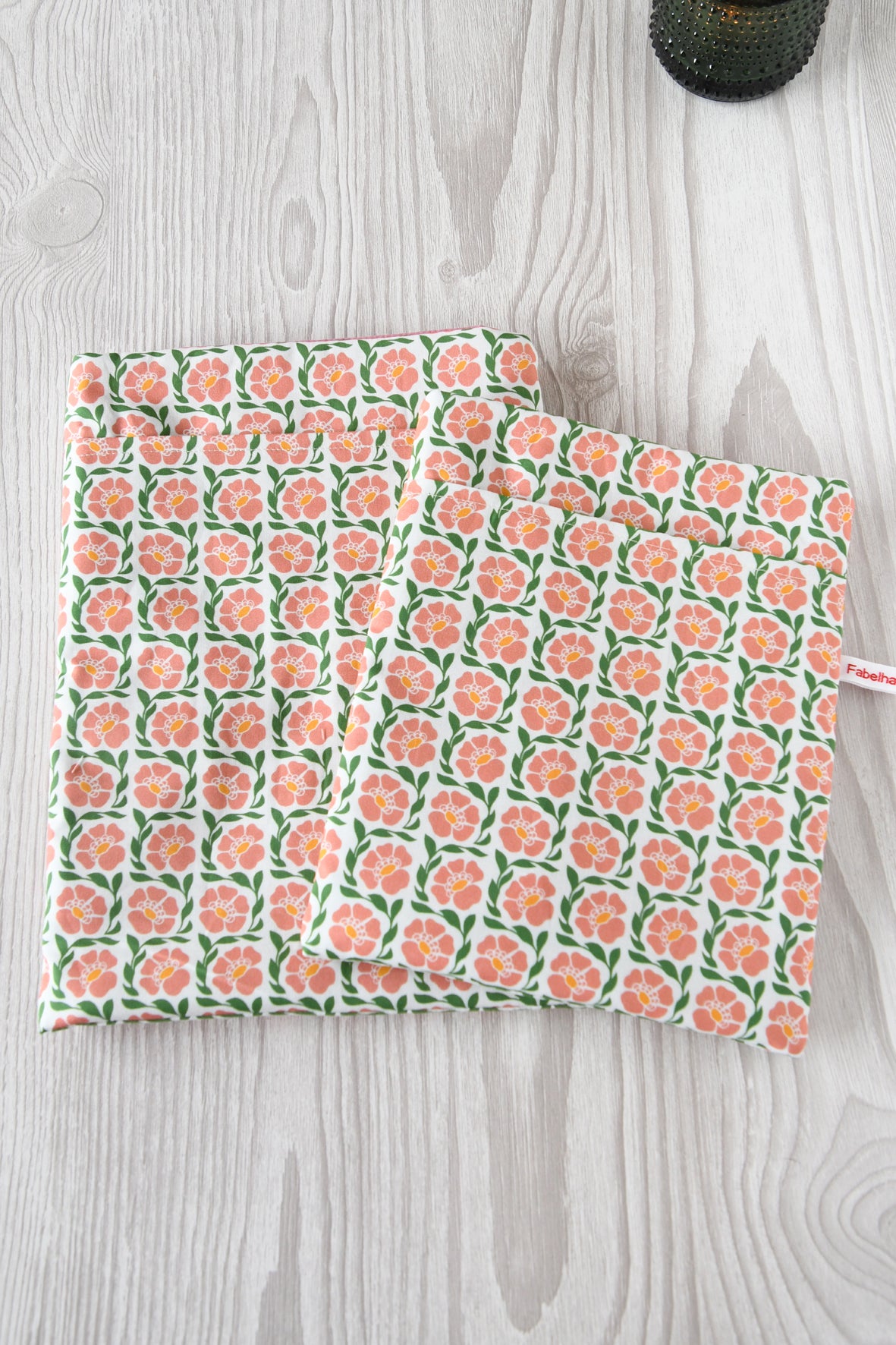 Größenvergleich der Buchtasche "Fanny" im rosafarbenden Blumenmuster: Links die große Buchtasche L für Hardcover-Bücher und Tablets, rechts die Standardgröße M für Taschenbücher, nebeneinander auf einem hellen Hintergrund.