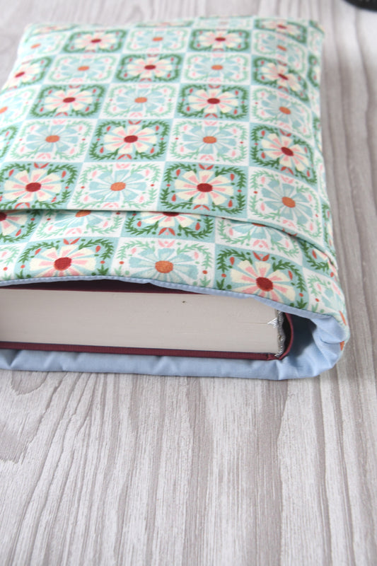 Große Buchtasche „Elisa“ in Größe L im mintfarbenen Karo-Blumen-Design. Ein dicker Hardcover-Wälzer mit ca. 500 Seiten ist passgenau in die Stoffhülle eingesteckt.
