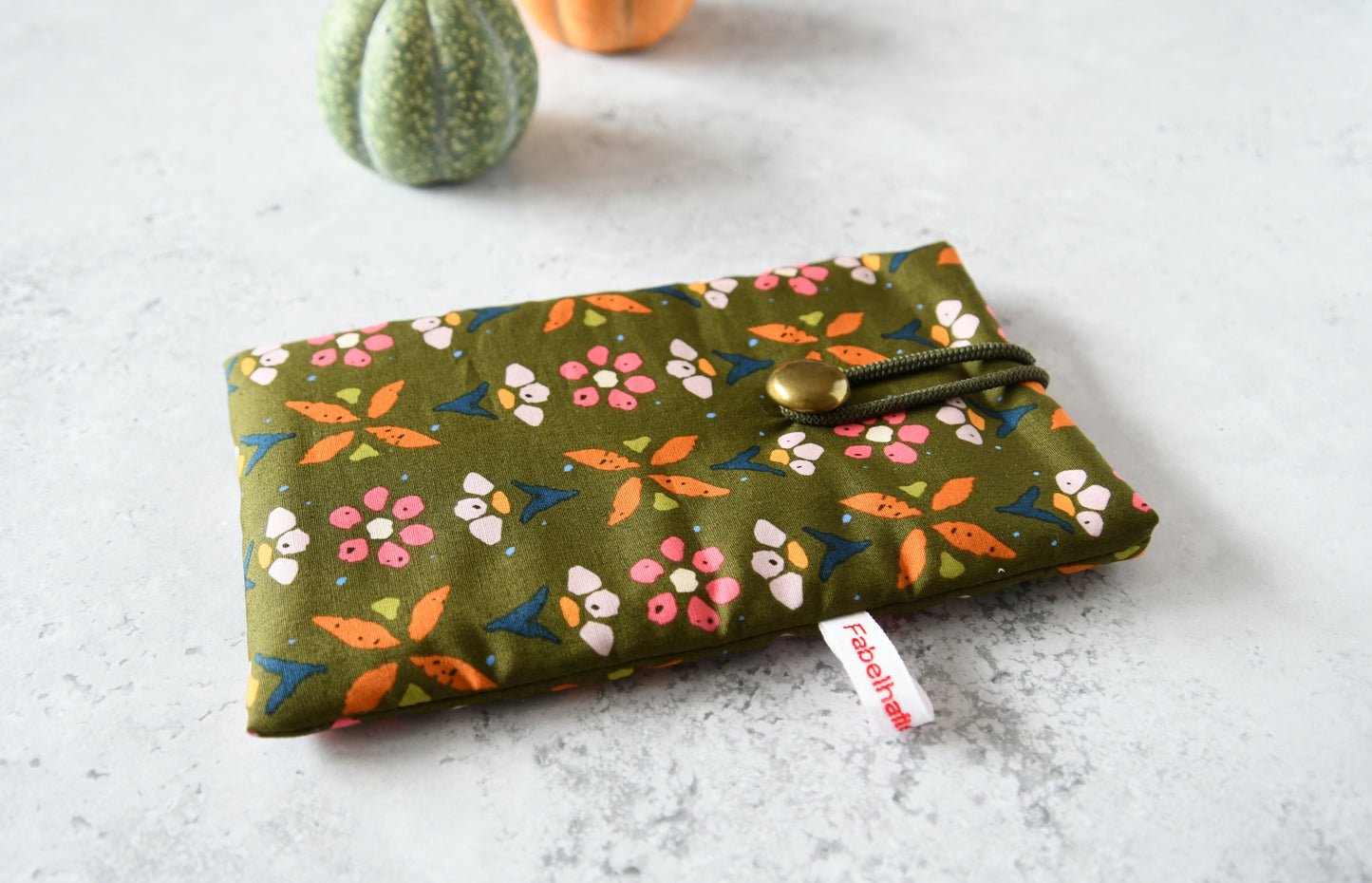 Handgenähte Stoff-Handytasche und Brillenetui mit buntem Blumenmuster auf grünem Hintergrund von Fabelhafte Werkstatt Bremen.