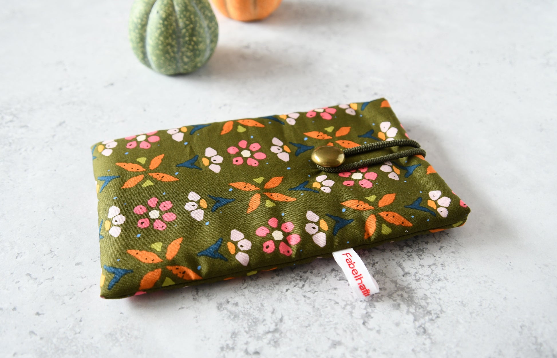 Handgenähte Stoff-Handytasche und Brillenetui mit buntem Blumenmuster auf grünem Hintergrund von Fabelhafte Werkstatt Bremen.
