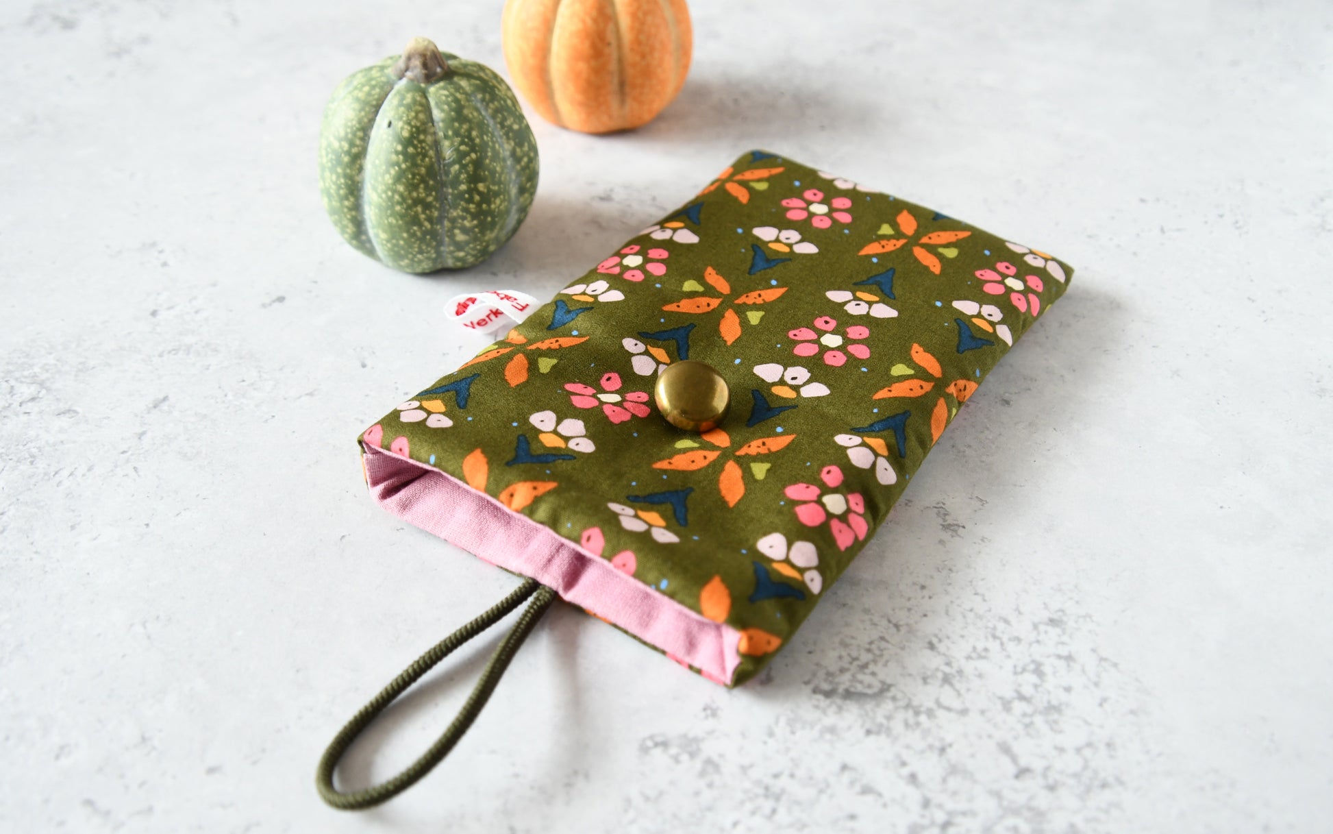 Nahaufnahme des floralen Baumwollstoffes mit Knopf und Gummiband-Verschluss der Fabelhaften Werkstatt.