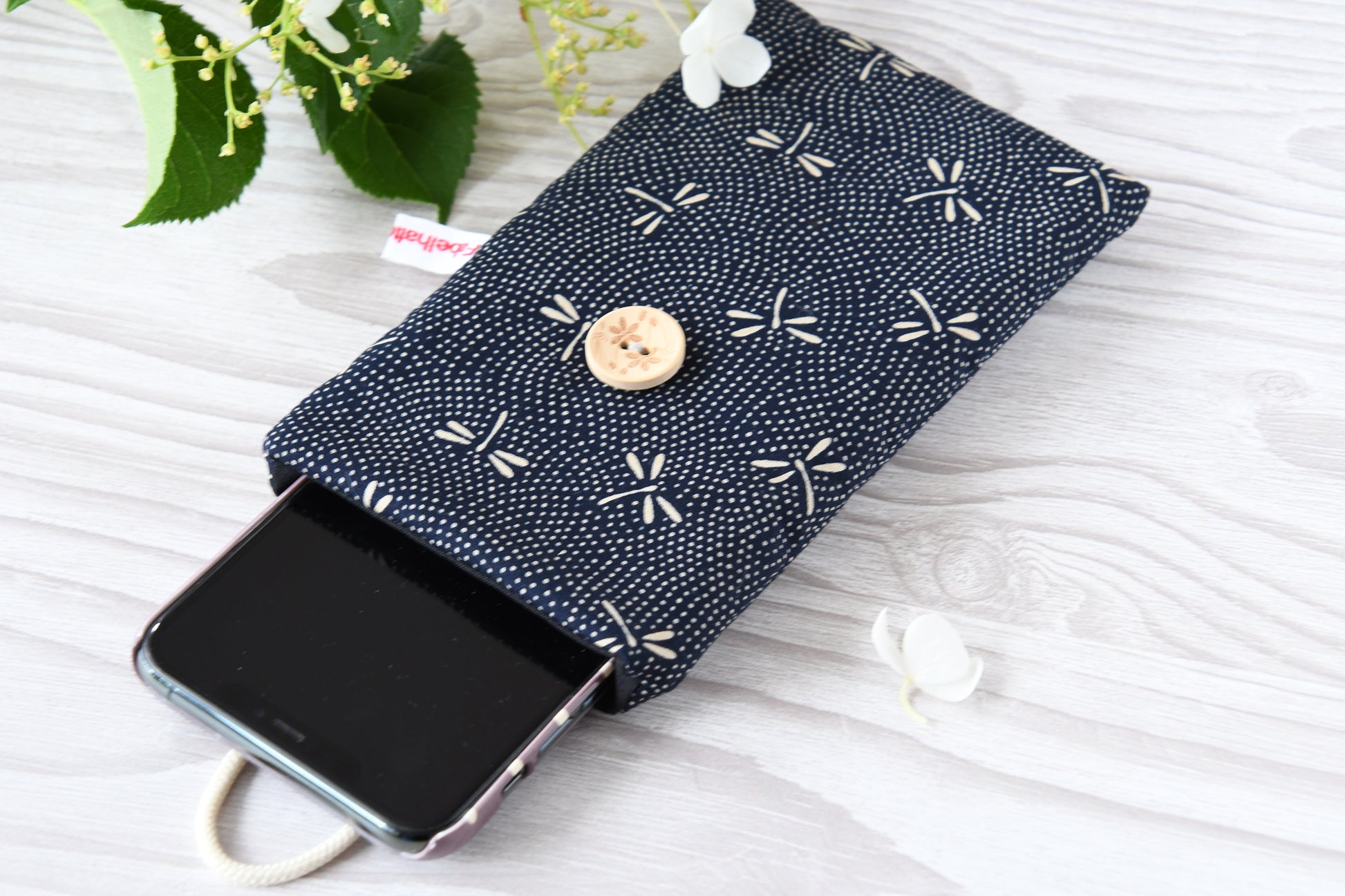 Geöffnete Stoff-Handyhülle mit einem Smartphone, das darin sicher vor Kratzern geschützt wird.