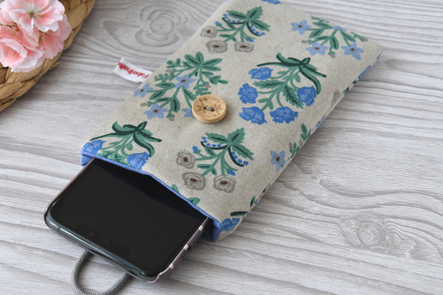 Weich gepolsterte Handyhülle mit geblümtem Stoff, geöffnet mit einem Handy als Inhalt.