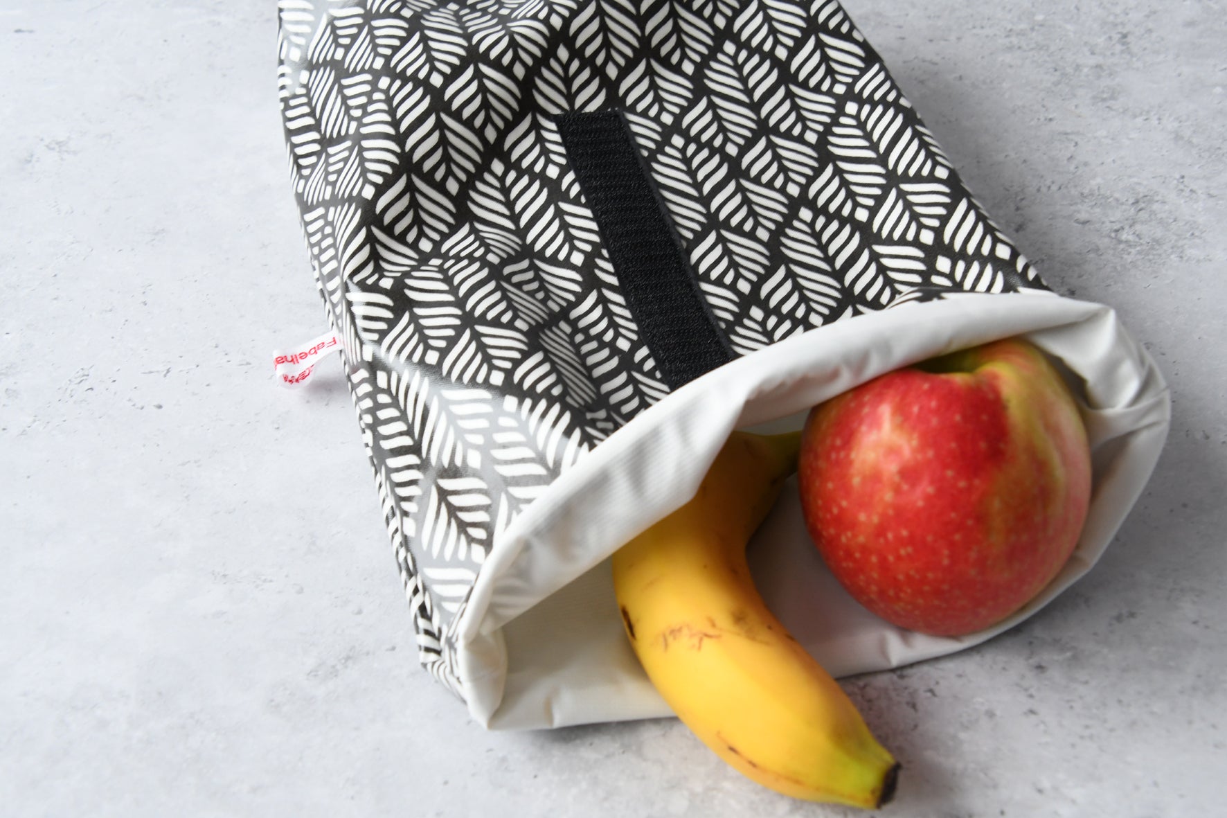Geöffneter Lunchbag "Ella" von Fabelhaftewerkstatt, gefüllt mit gesundem  Obst für unterwegs.