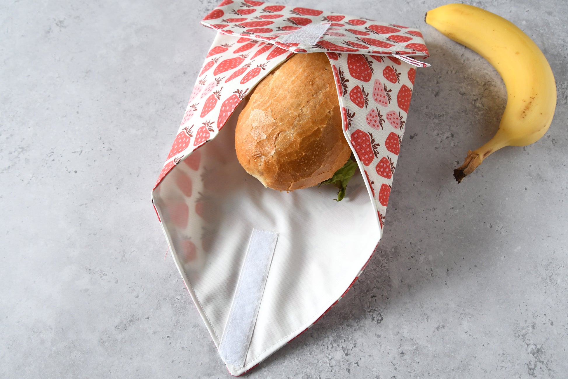 Schritt-für-Schritt-Anleitung: Der waschbare Sandwich Wrap ist an drei Seiten um das Brötchen gefaltet, kurz vor dem Verschließen.