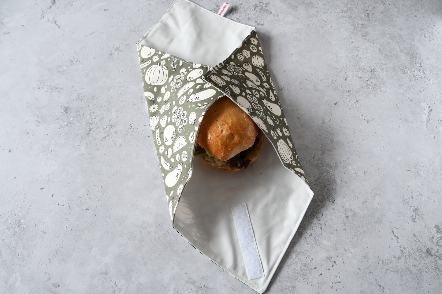Belegtes Brötchen im Sandwich Wrap, an zwei Seiten sauber eingeschlagen.