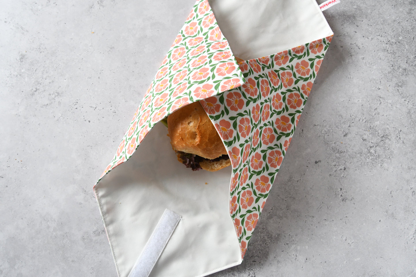 Belegtes Brötchen im Sandwich Wrap, an zwei Seiten sauber eingeschlagen.
