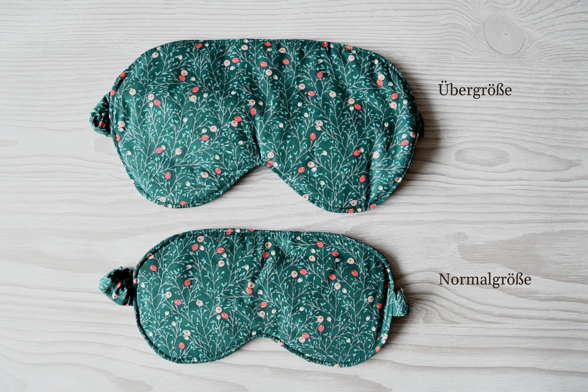 Vergleich der Normalgröße und Übergröße der handgenähten Schlafmaske im Beeren-auf-Petrol-Design