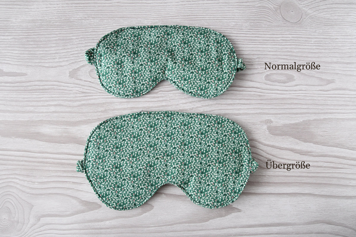 Vergleich der Normalgröße und Übergröße der handgenähten Schlafmaske Anthea mit botanischem Print auf Grün